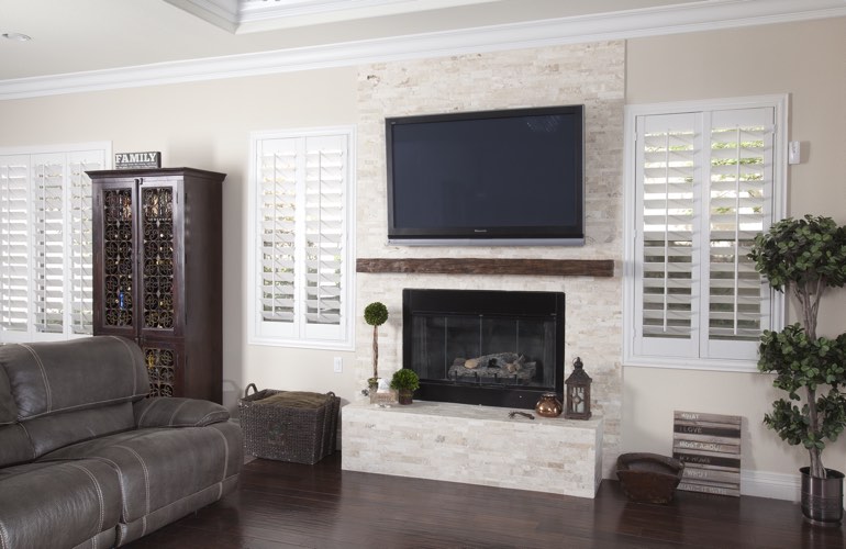 White plantation shutters in a Fort Lauderdale living room with dark hardwood floors.